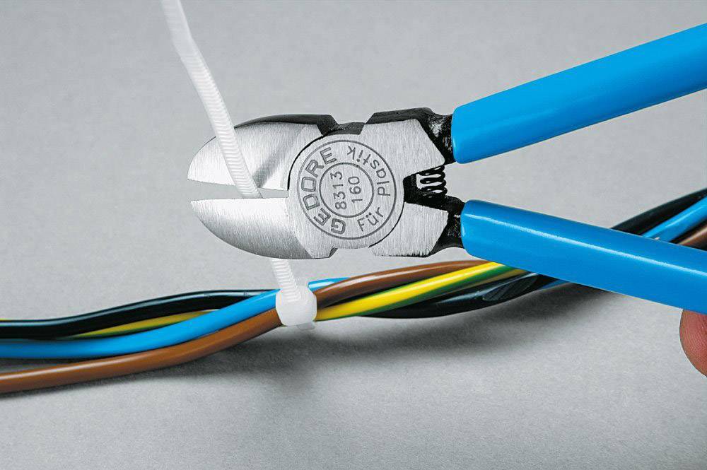 Zange schneidet ein weißes Kabelband, das bunte Drähte bündelt. Blauer Griff, Werkzeugname 'GEDORE' sichtbar.