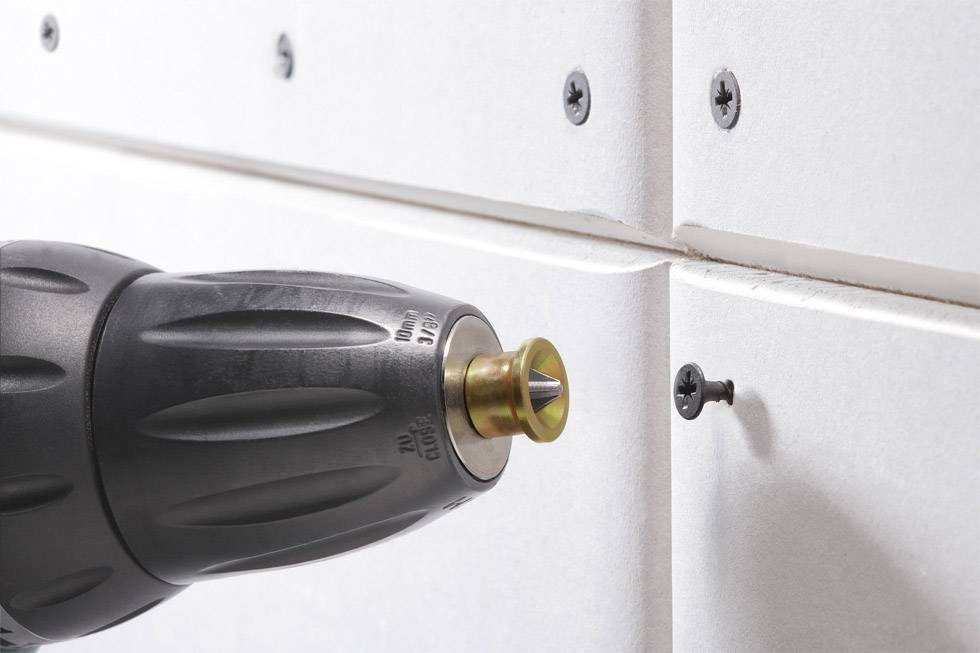 Bohrer auf Schraube gerichtet, befestigt Gipskartonplatten an der Wand.