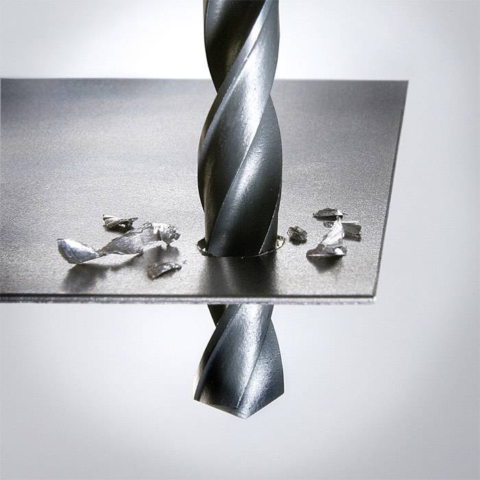 Ein Bohrer durchdringt eine Metallplatte, erzeugt Späne.