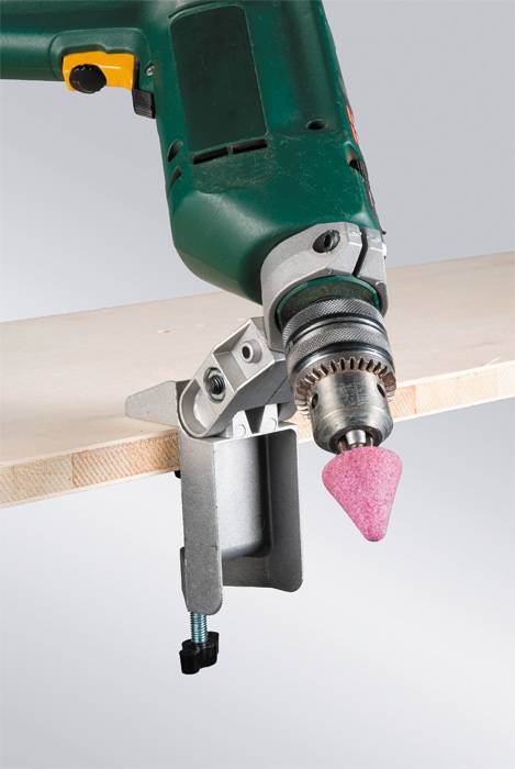 Bohrmaschine mit Schleifaufsatz schleift die Kante einer Holzplatte. Das Gerät ist an einem Metallhalter befestigt.