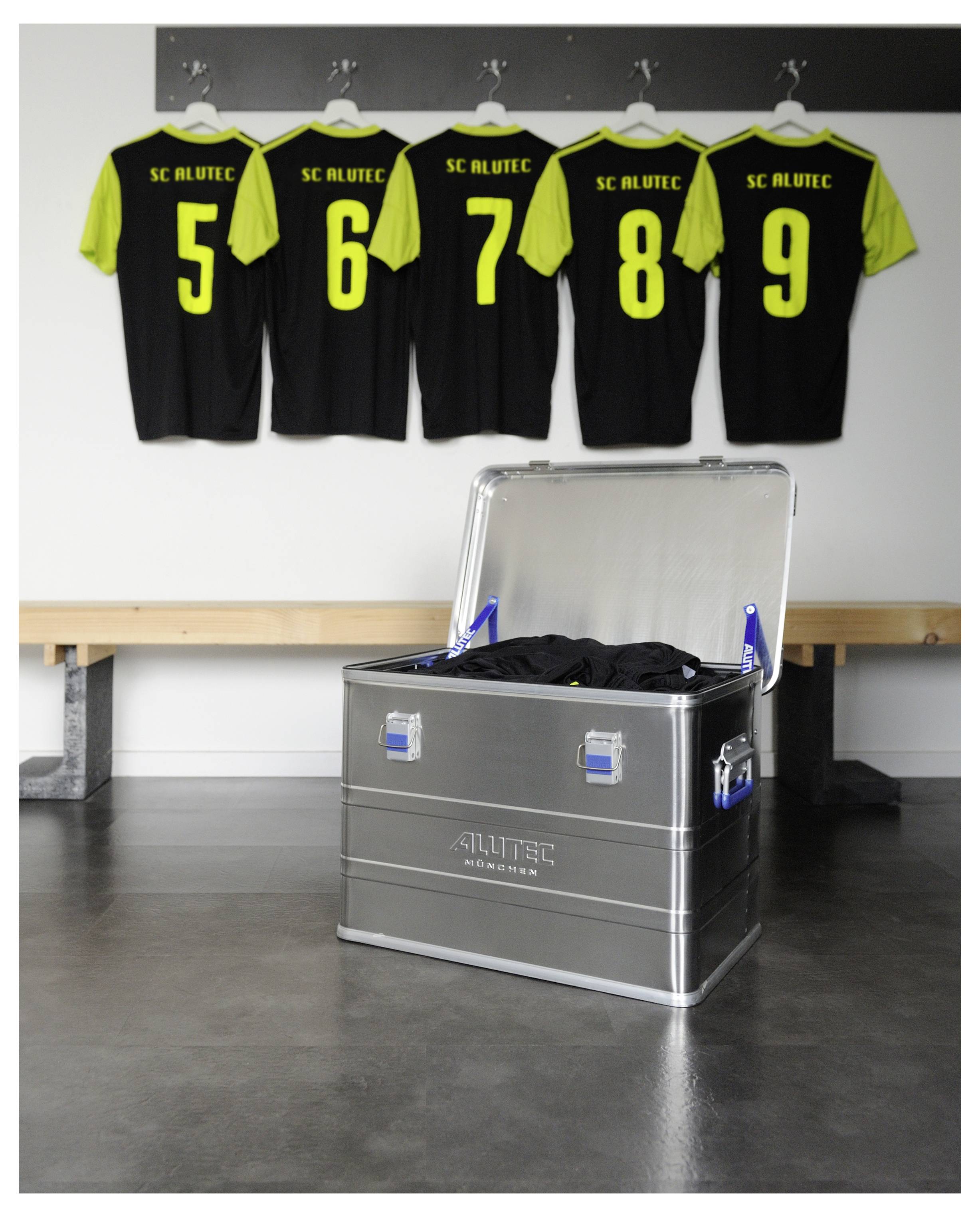 Ein Sportumkleideraum mit fünf schwarz-gelben Trikots, die an Haken über einer offenen Metallbox hängen, die Ausrüstung enthält.