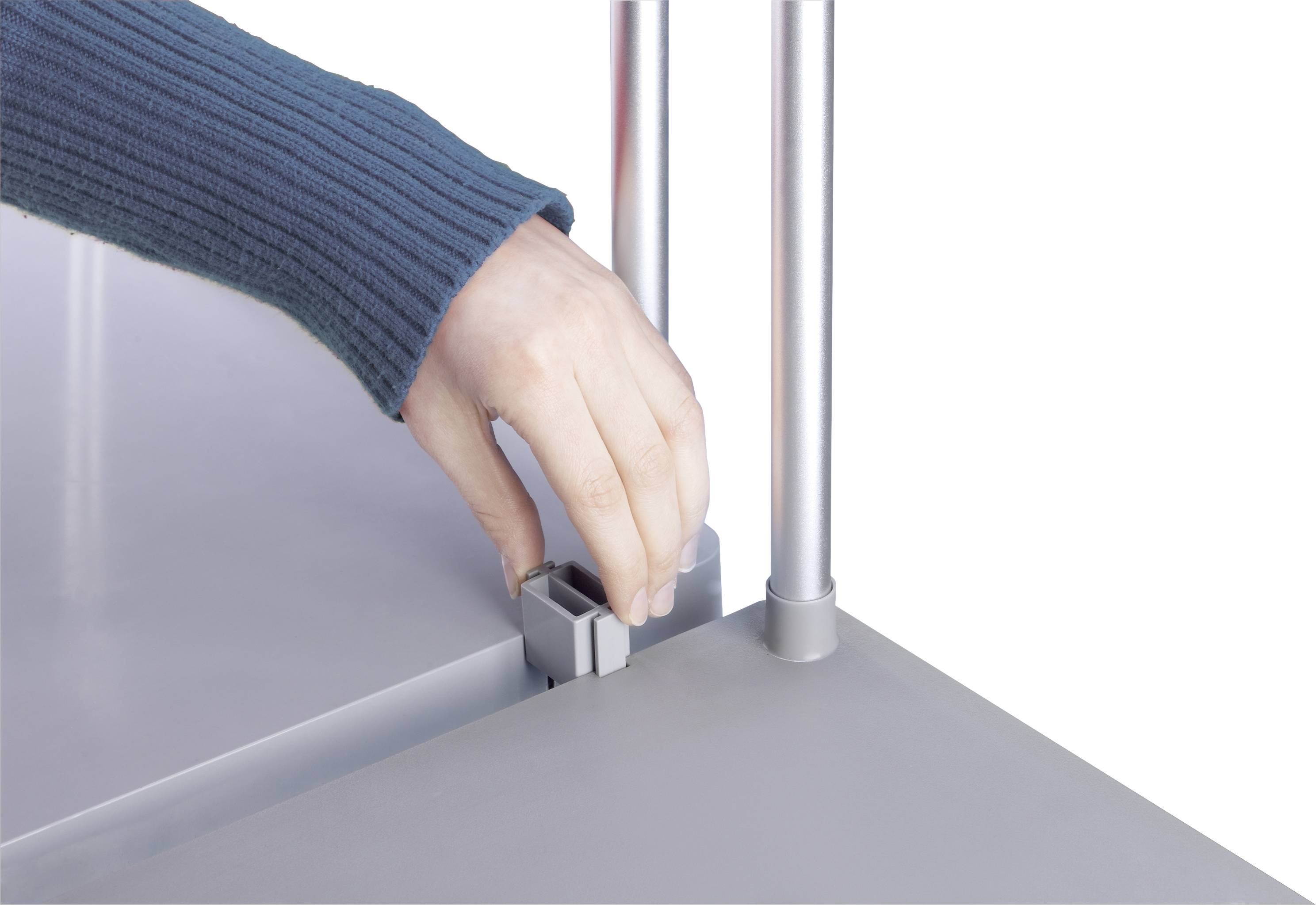 Eine Hand stellt den Hebel eines grauen Tischs ein.