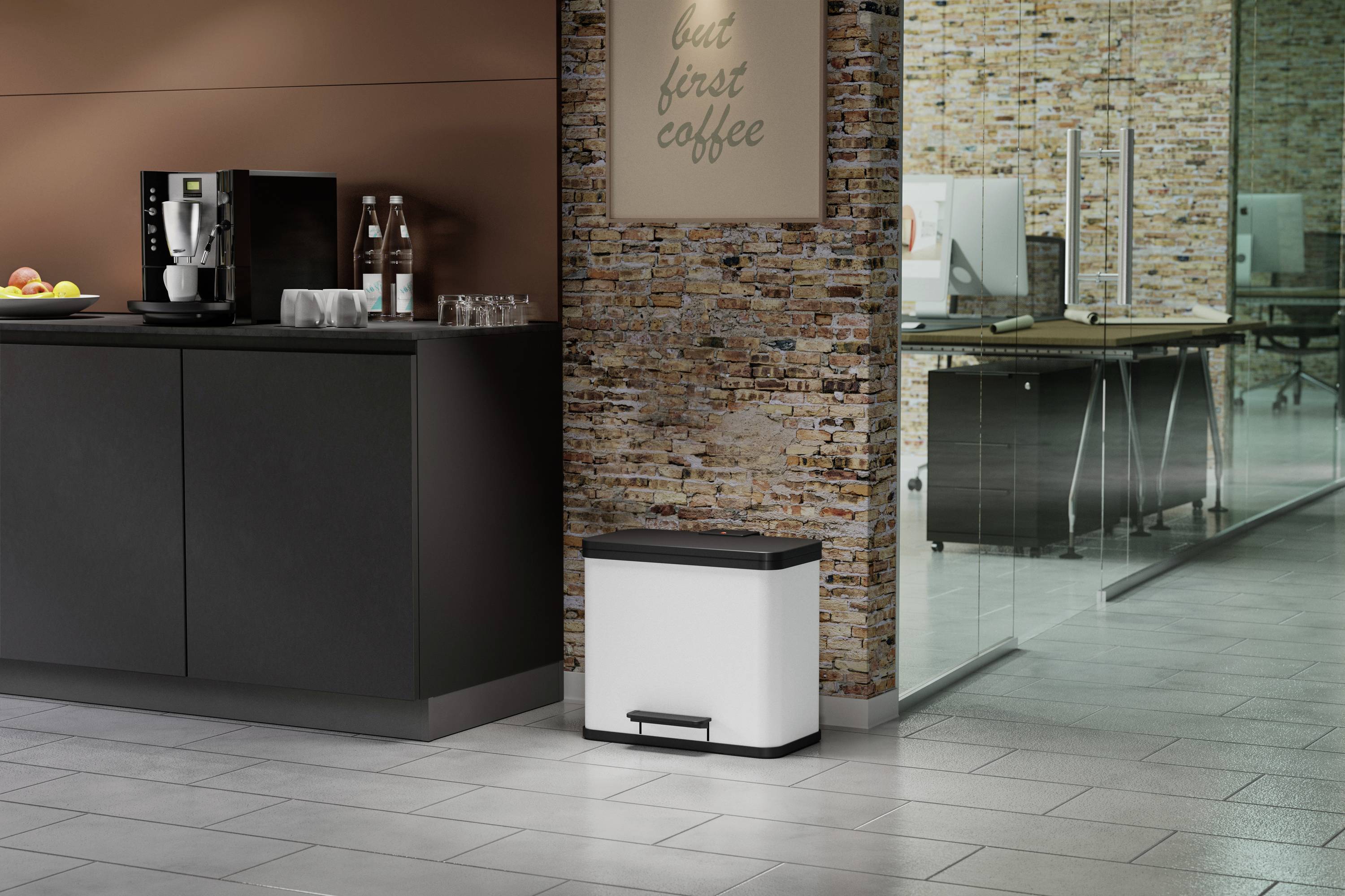 Ein moderner Büroraum mit Kaffeemaschine und Gläsern auf einem Schrank, einem Mülleimer auf dem Boden und dem Schild 'but first coffee' an der Wand.