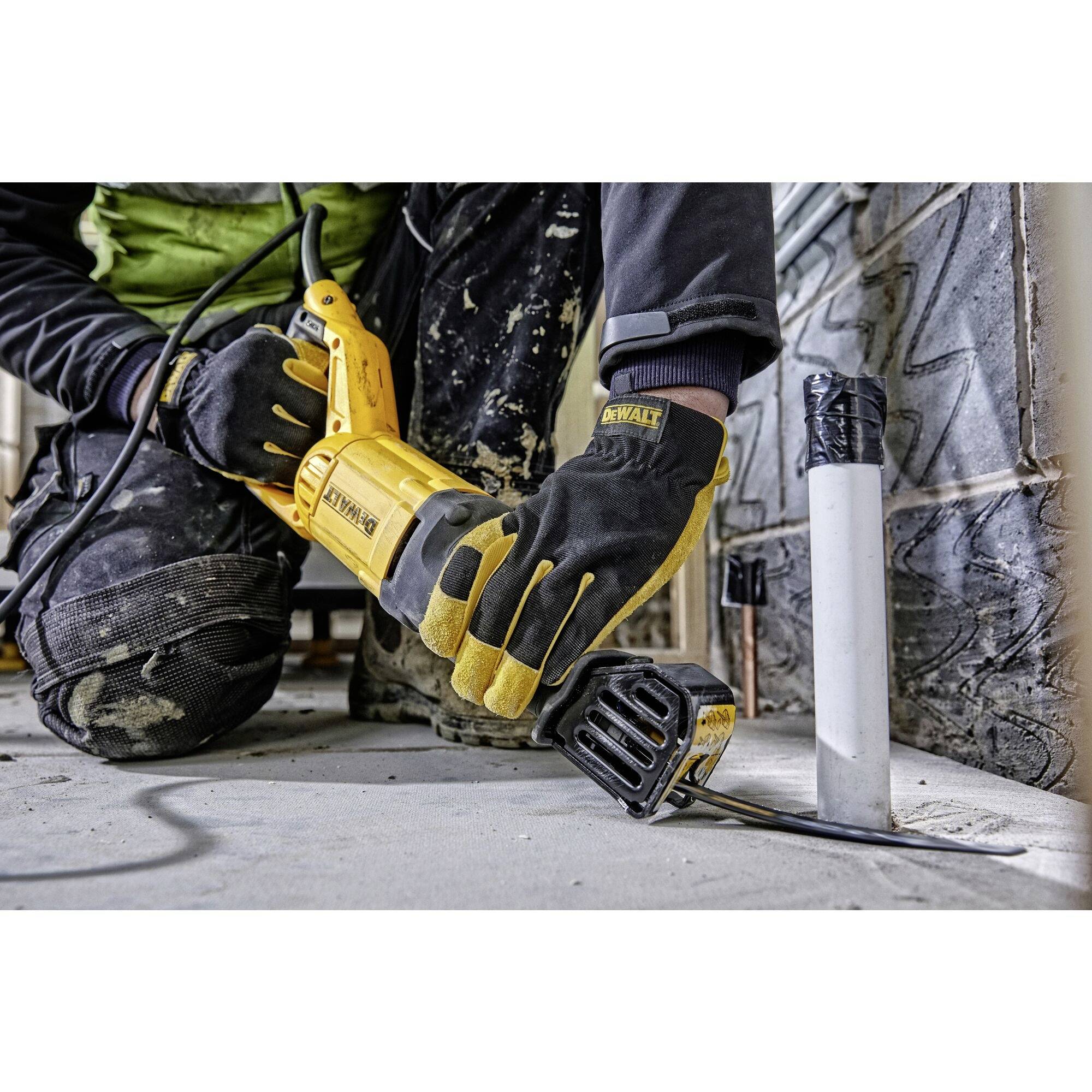 Eine Person benutzt eine elektrische Säbelsäge, um ein Metallrohr zu durchtrennen. Sie trägt Schutzausrüstung einschließlich Handschuhe.