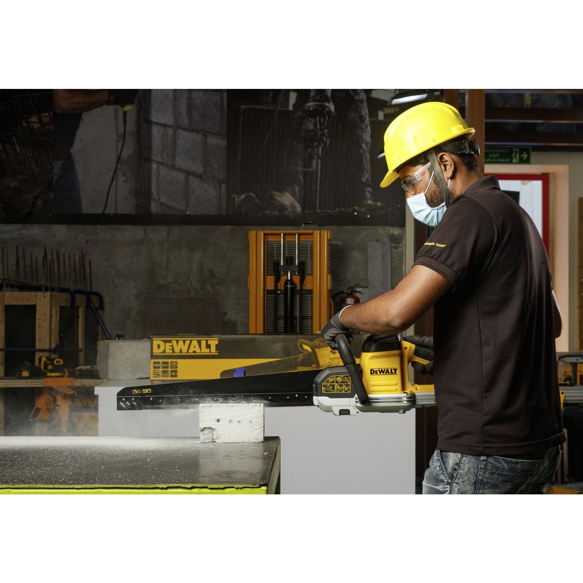 Ein Arbeiter trägt Helm und Schutzmaske und verwendet ein DeWalt-Werkzeug, um ein Material in einer Werkstatt zu schneiden.