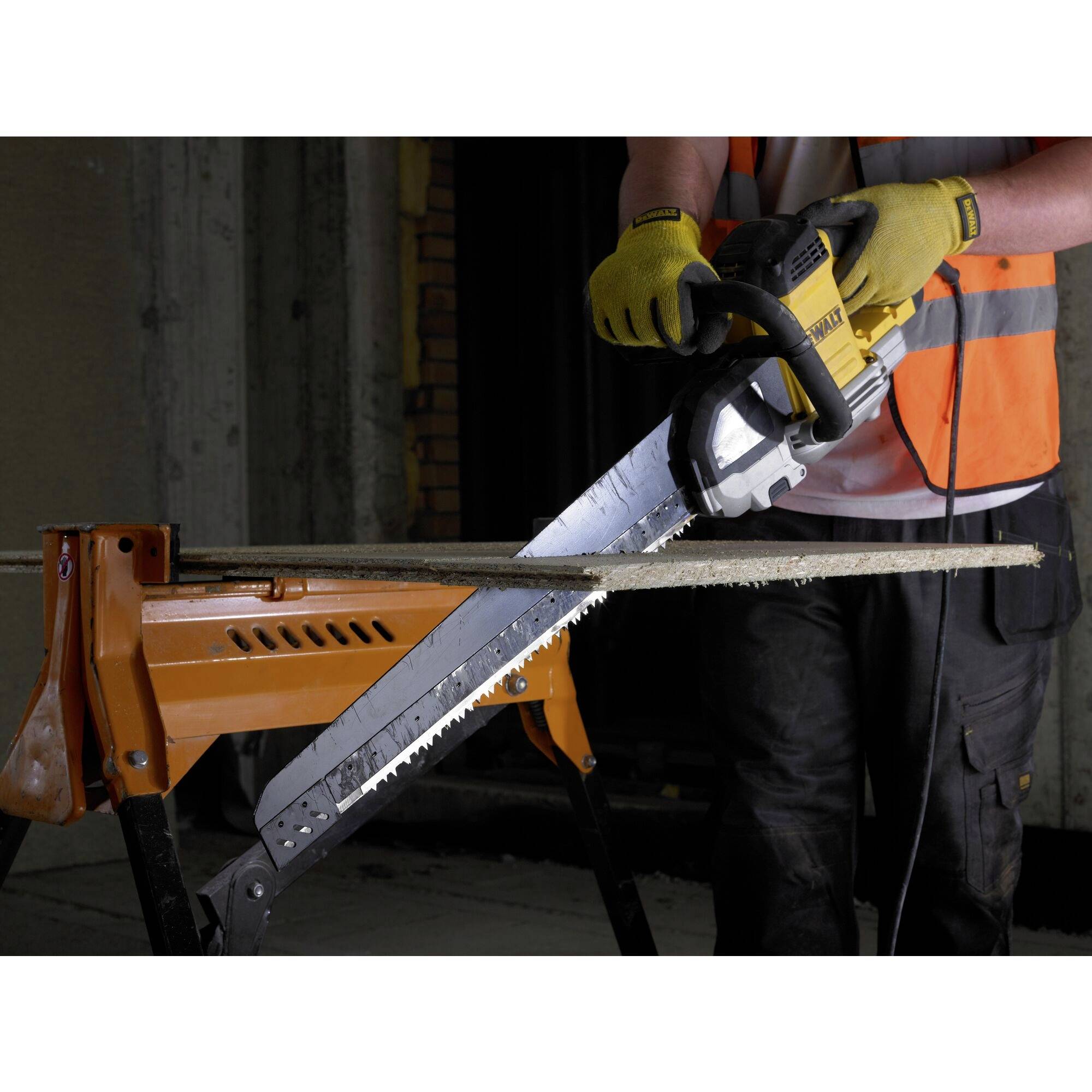 Eine Person in Schutzkleidung schneidet mit einer elektrischen Säge ein Holzbrett, das auf einem Metallgestell liegt.