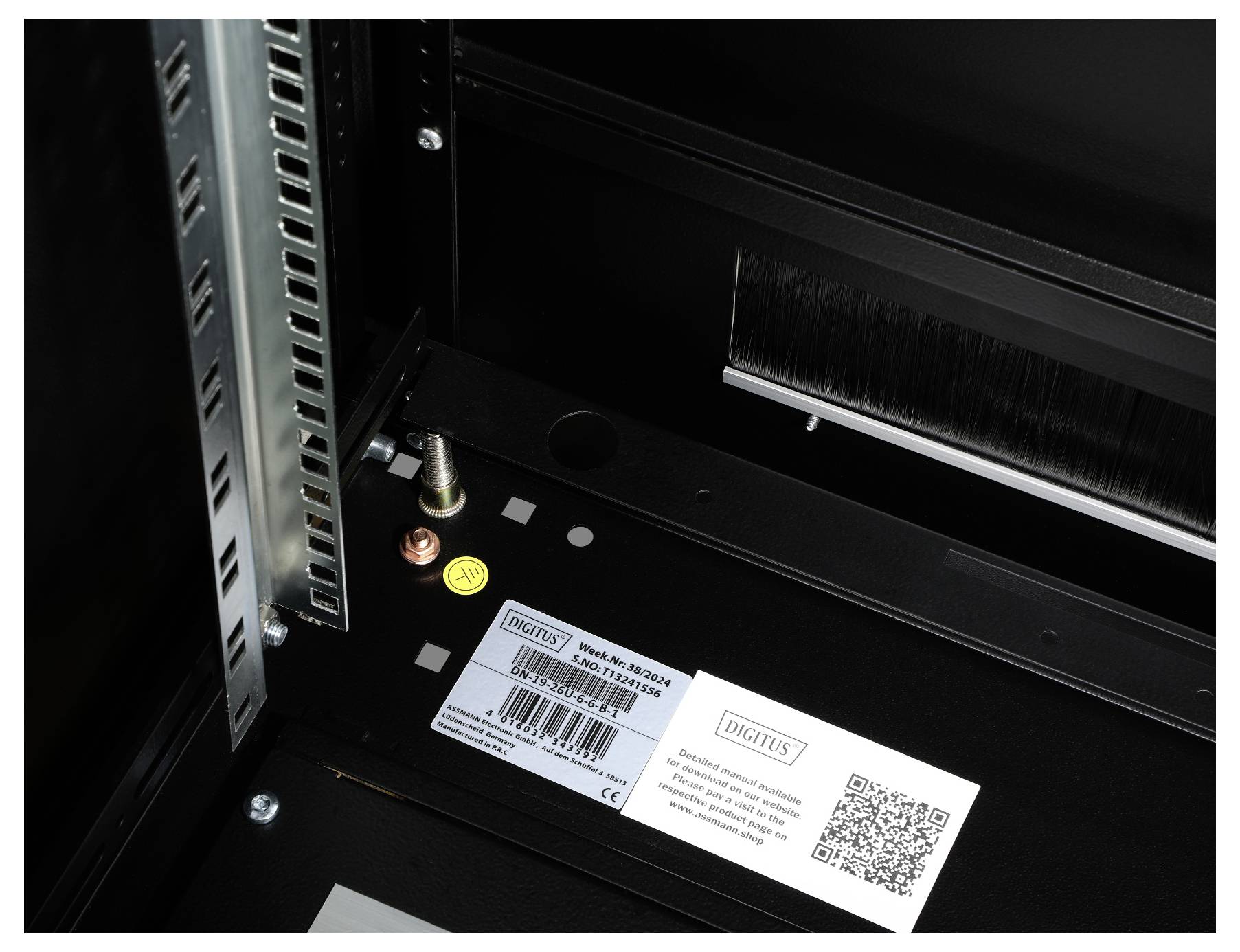 Ein Serverrack mit einer Marke 'Digitus' und QR-Code auf einem Aufkleber. Beschriftung 'Model: DK-19xxM-SW'. Links Metallrahmen sichtbar.