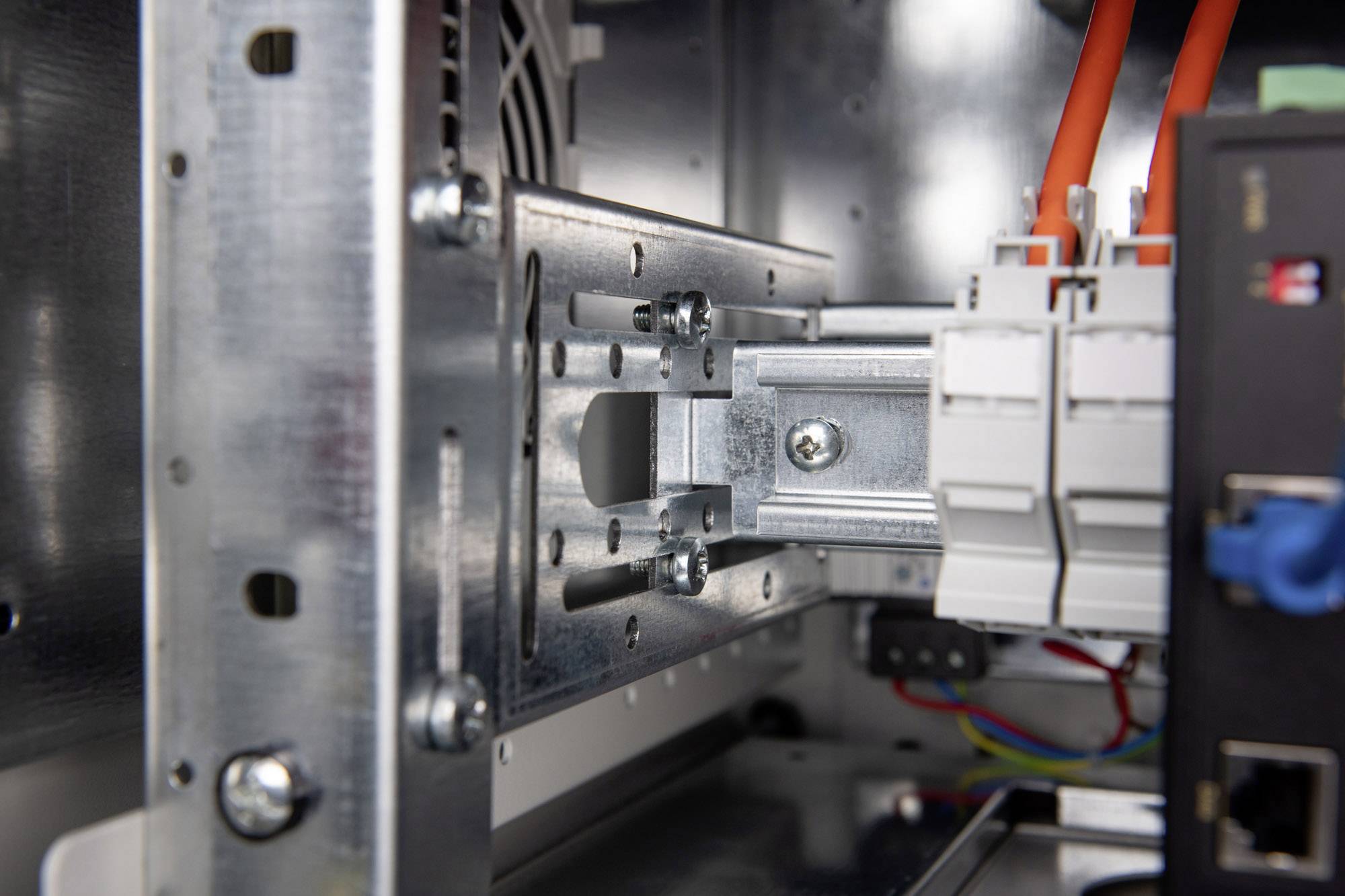 Ein Metallrahmen in einem elektrischen Schaltschrank mit farbigen Kabeln und Steckverbindungen.