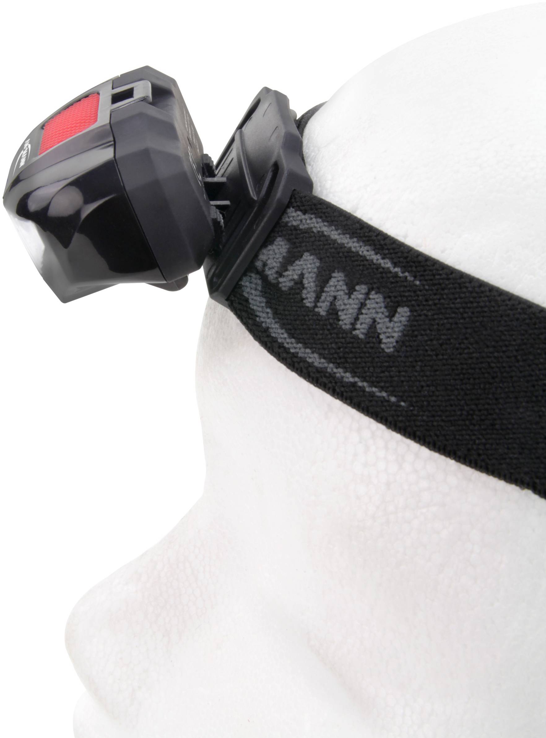 Person mit Stirnlampe auf dem Kopf, auf einem schwarzen elastischen Band befestigt, von der Seite betrachtet.