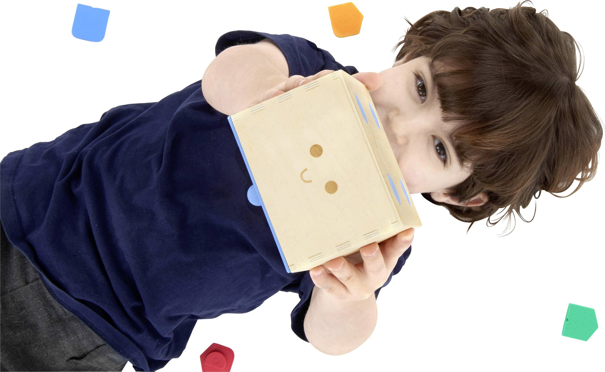 Ein Kind hält einen würfelförmigen Roboter und lächelt. Bunte geometrische Formen sind um das Kind verteilt.