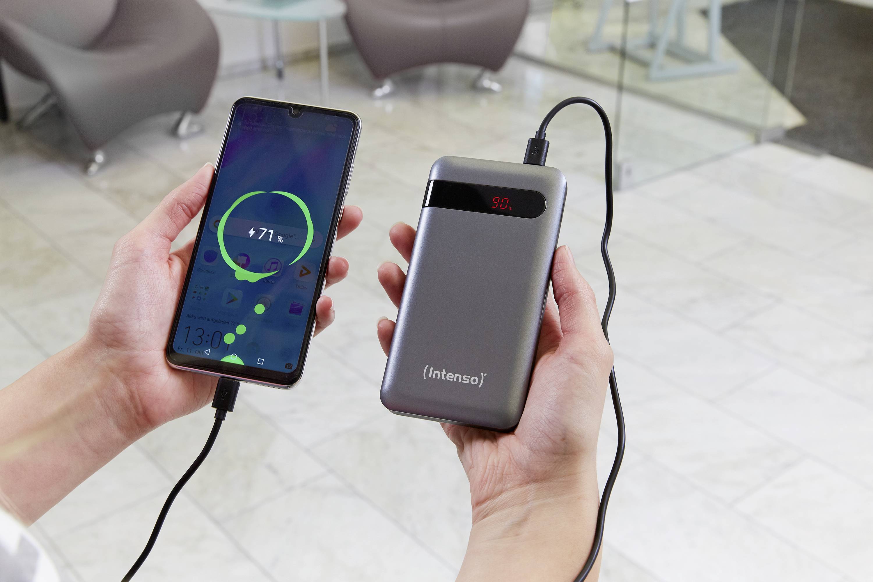 Eine Hand hält ein Smartphone mit Ladeanzeige, verbunden mit einer tragbaren Powerbank in der anderen Hand. Der Akku zeigt 50% an.