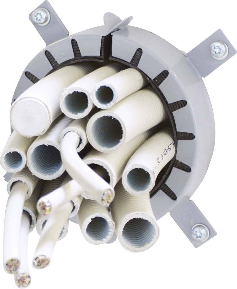 Mehrere weiße Kabel und Leitungen ragen aus einer runden, grauen Halterung, die an einer Wand montiert ist.