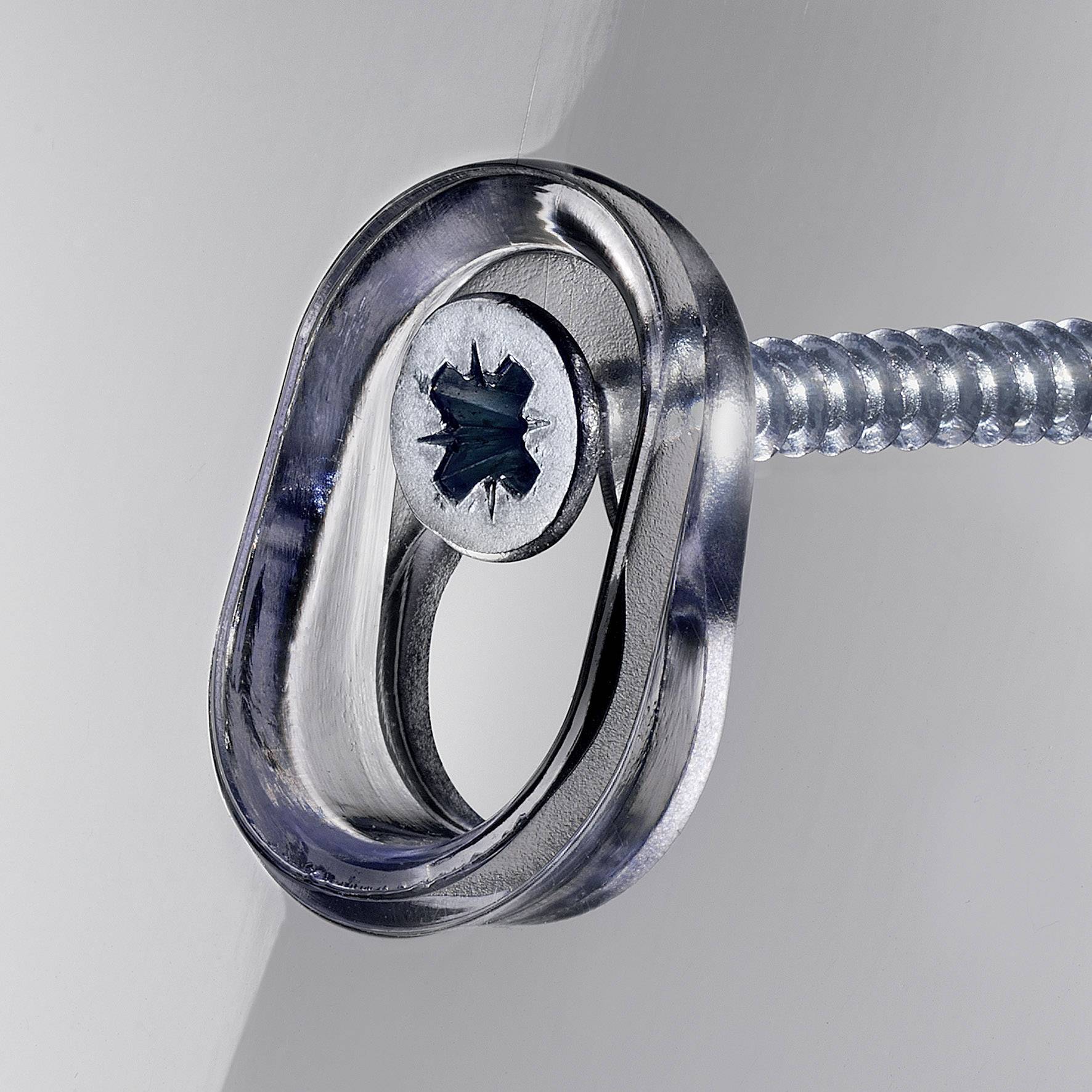 Eine silberne Schraube mit ovaler Öse ist in eine graue Wand geschraubt. Die Öse ist leicht geneigt.