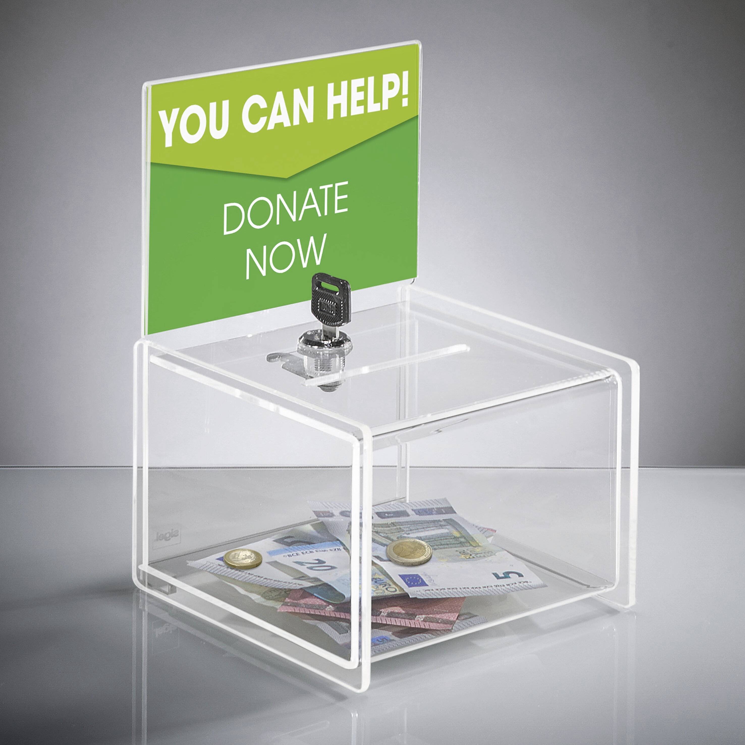 Eine transparente Spendenbox mit Bargeld und Münzen darin. Ein grünes Schild oben liest sich: 