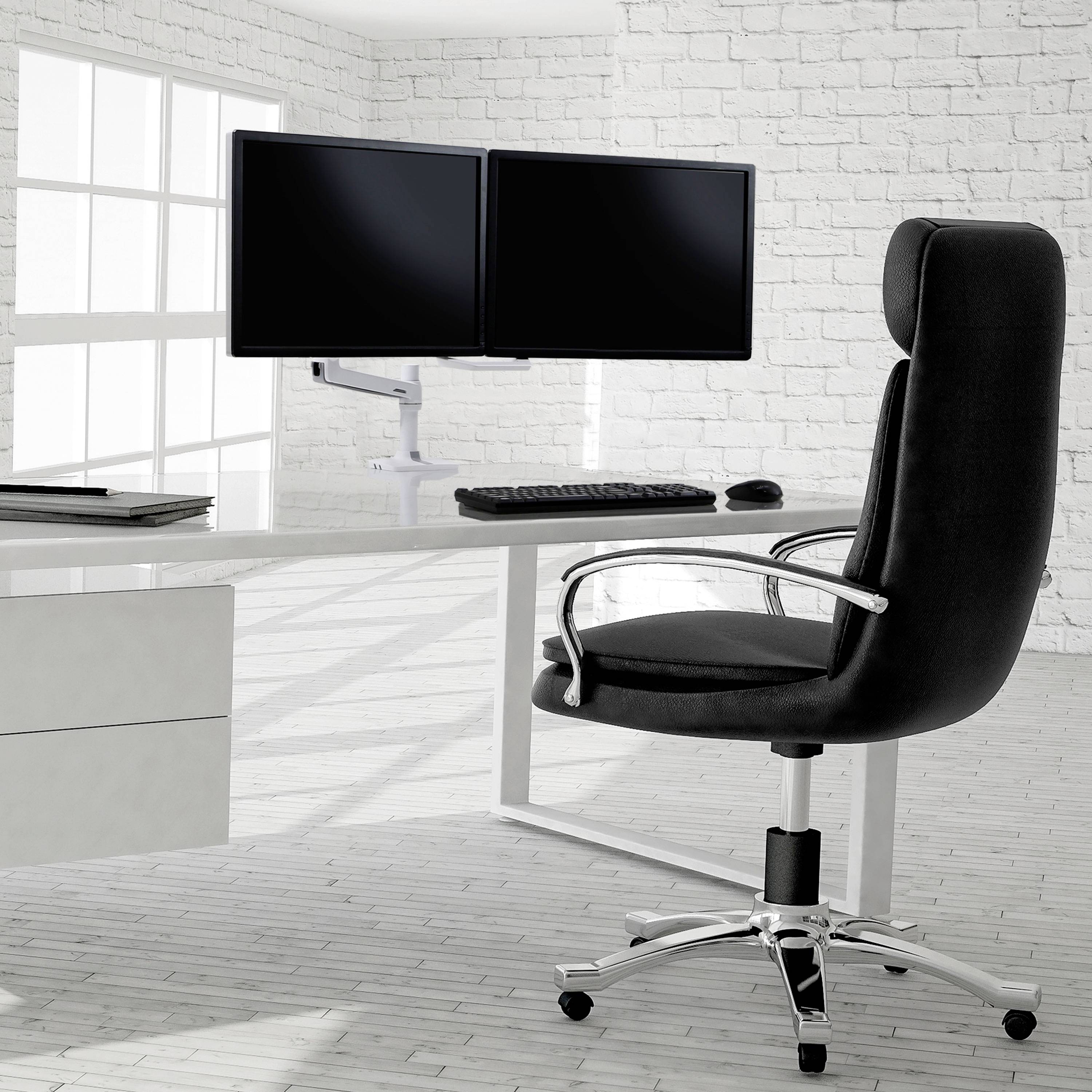 Ein moderner Bürostuhl steht vor einem weißen Schreibtisch mit zwei Monitoren, einer Tastatur und einer Maus in einem hellen Raum.