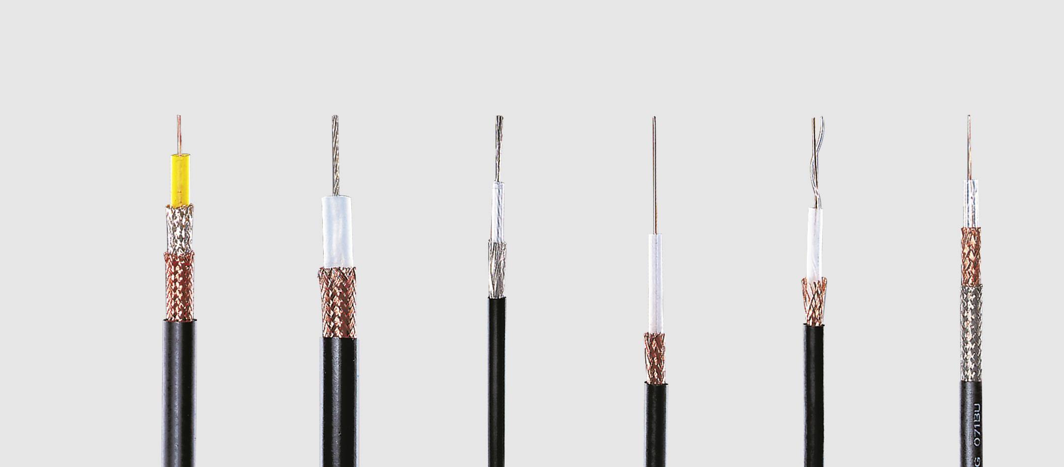 Mehrere Koaxialkabel unterschiedlicher Typen und Dicken stehen nebeneinander vor einem grauen Hintergrund.