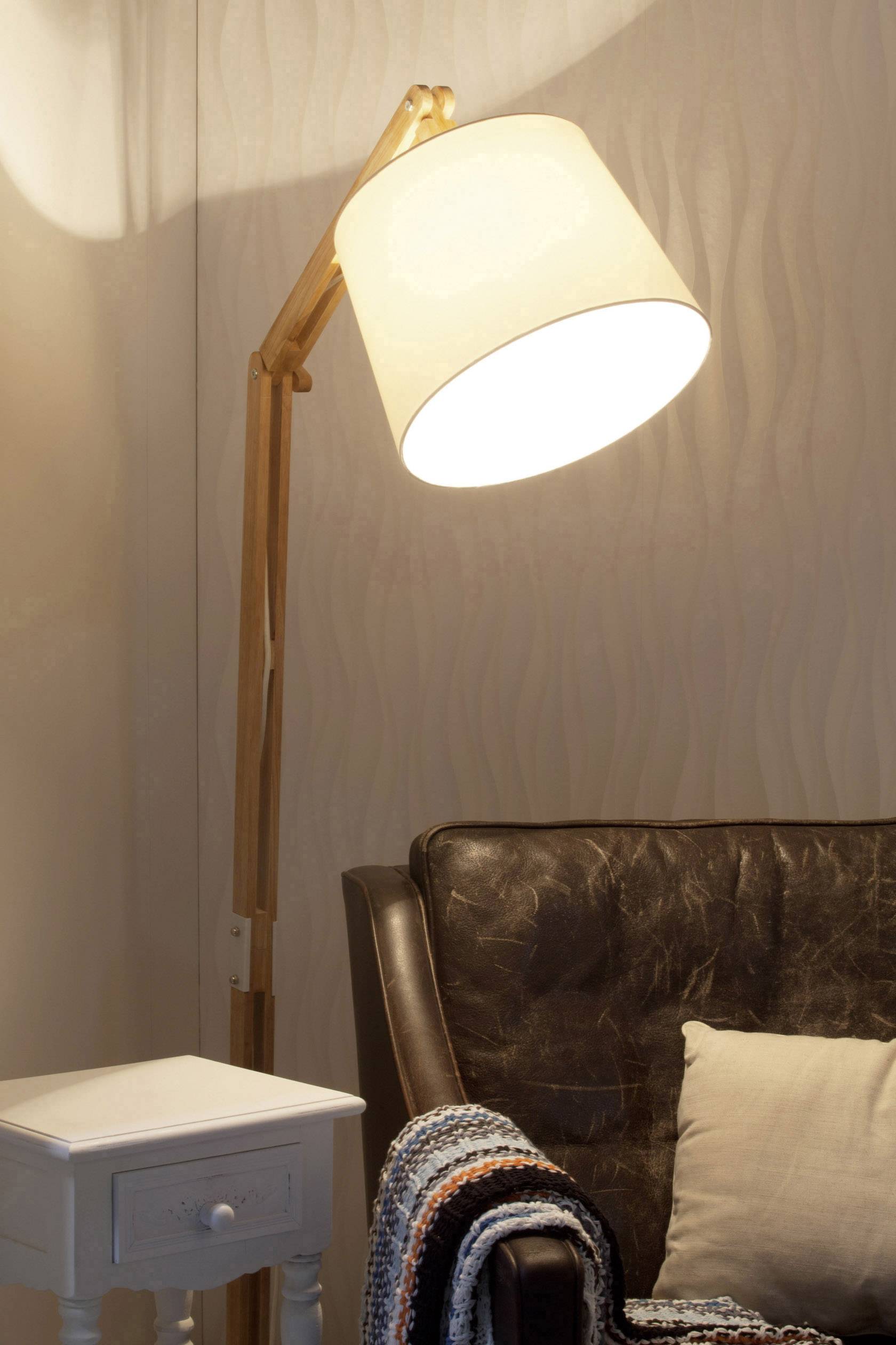 Stehlampe neben einem braunen Ledersessel mit Kissen und gehäkelter Decke, daneben ein kleiner weißer Beistelltisch.