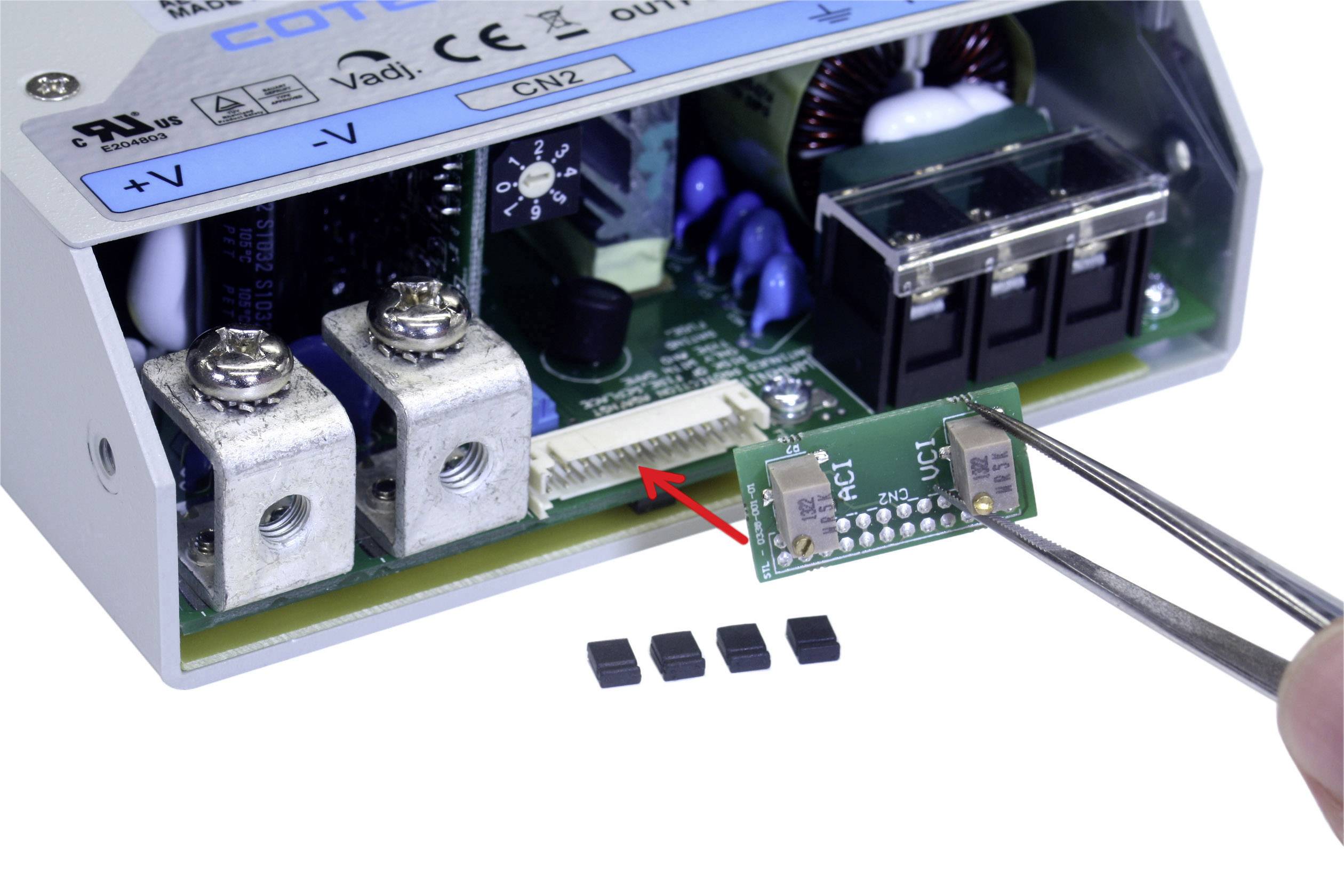 Elektronisches Bauteil wird mit einer Pinzette in einen Anschluss einer offenen Schaltung im Gerät eingeführt.