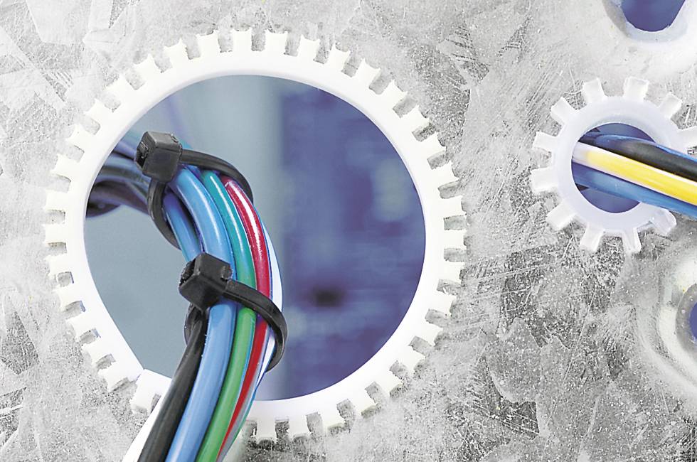 Bunte Kabel führen durch eine Zahnradscheibe in einer technischen Umgebung.
