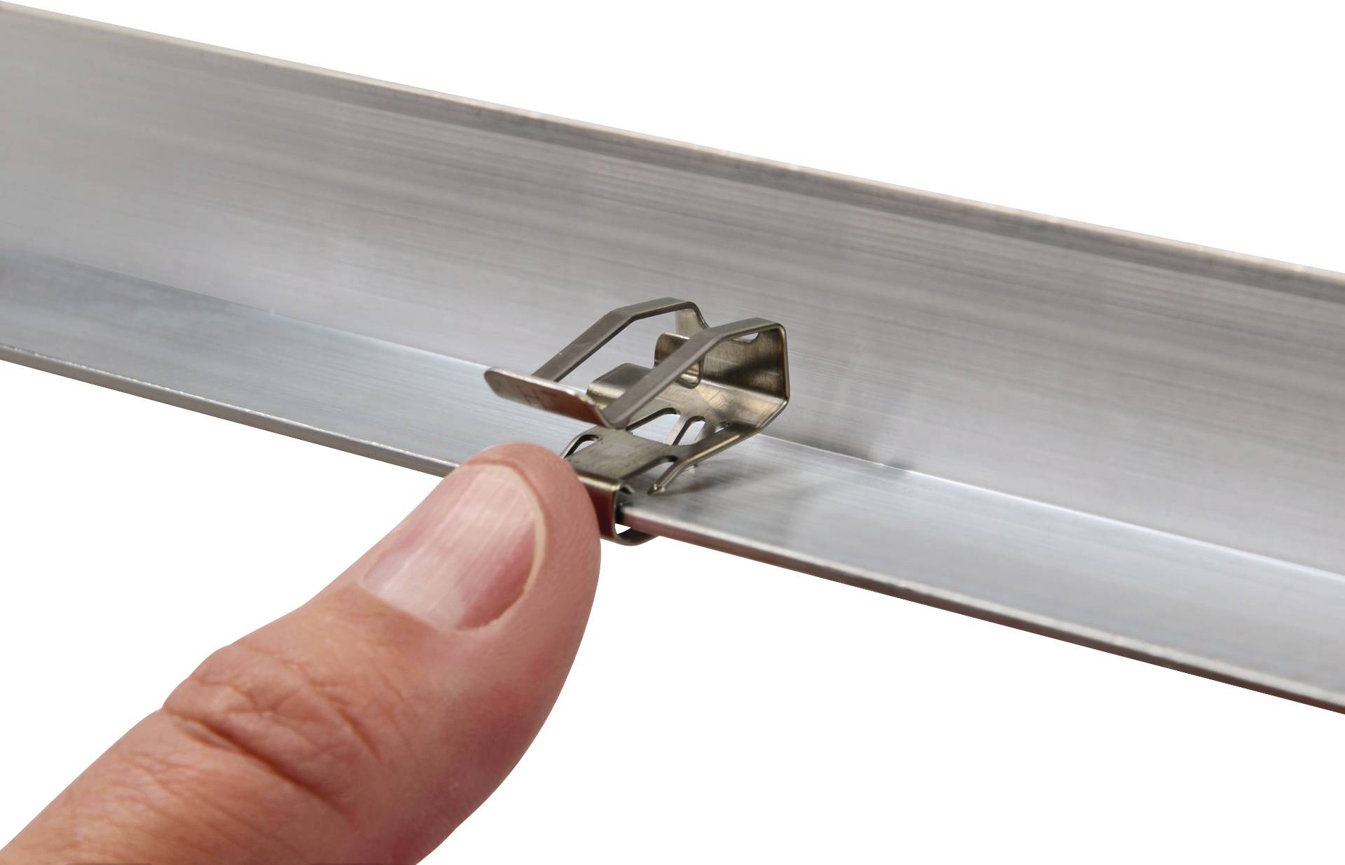 Nahaufnahme eines Fingers, der einen Metallclip in einer Schiene arretiert. Der Clip hält ein Stück Metall stabil.