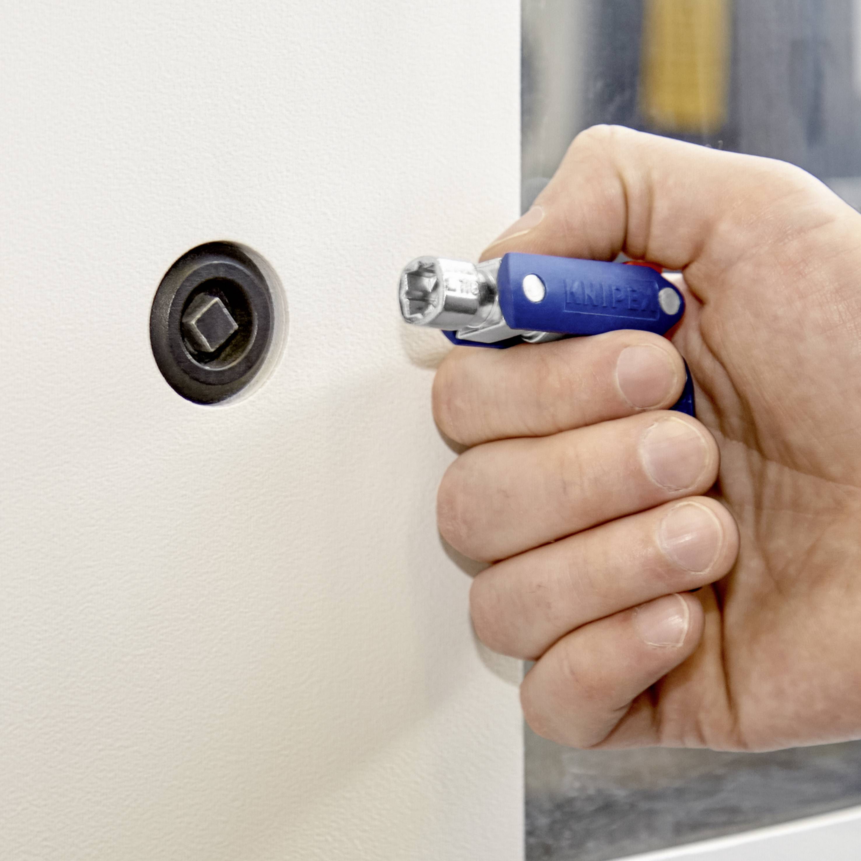 Eine Hand hält ein blaues Multifunktionswerkzeug, das in einem Schloss mit einer sternförmigen Öffnung steckt.