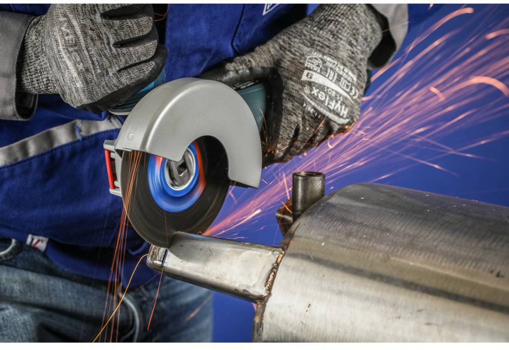 Arbeiter verwendet Winkelschleifer, um Metallrohr zu schneiden. Funken fliegen, während das Werkzeug das Metall berührt.