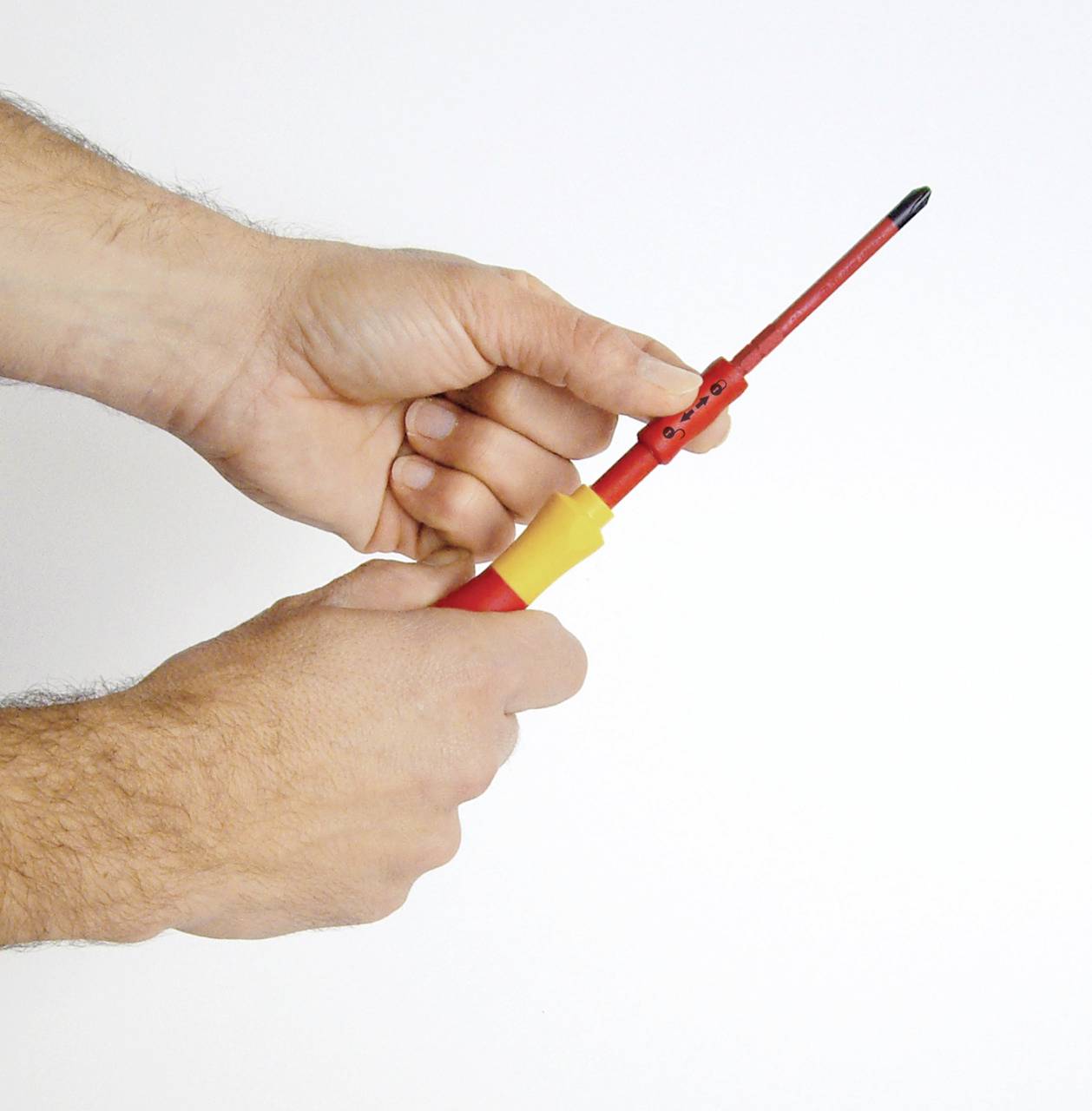 Zwei Hände halten einen isolierten Schraubendreher mit rotem und gelbem Griff, geeignet für Arbeiten an elektrischen Anlagen.