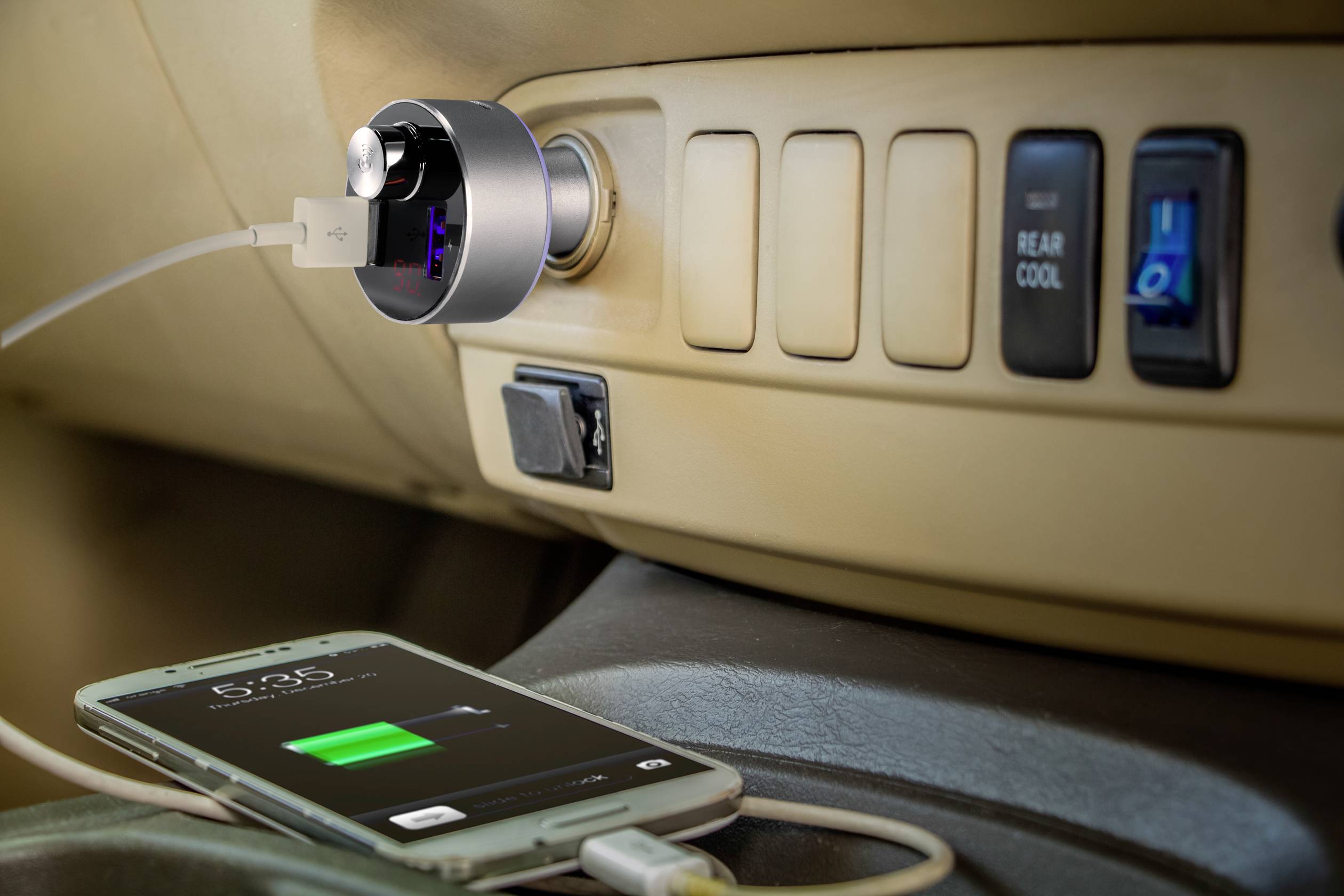 Ein Smartphone wird im Auto mit einem USB-Kabel aufgeladen, das an einen Ladeadapter im Zigarettenanzünder-Steckplatz angeschlossen ist.