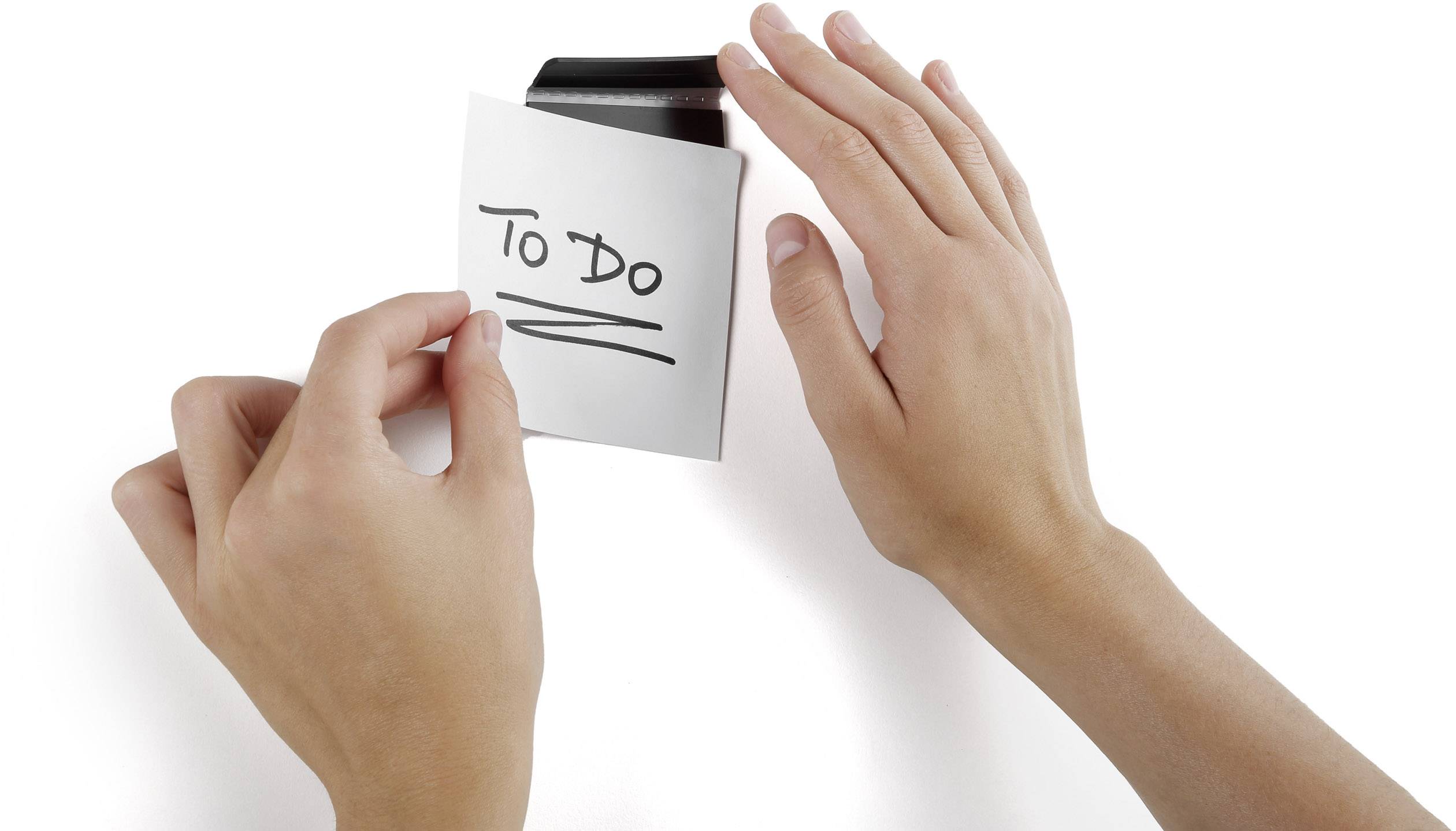 Zwei Hände befestigen eine Notiz mit der Aufschrift 'To Do' an einer schwarzen Klammer.