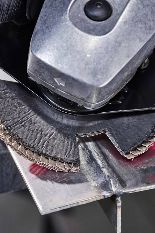 Ein Winkelschleifer schneidet eine Metallplatte. Nahaufnahme zeigt Funkenflug und detailreiche Texturen des Metalls und Werkzeugs.