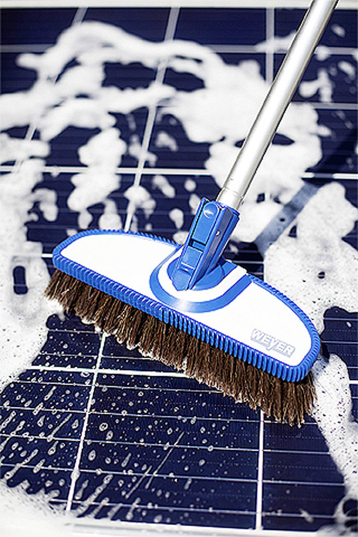 Ein Besen mit Seifenlauge reinigt eine Solarzelle.