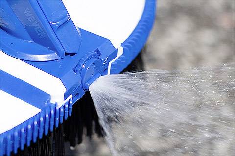 Blaue Bürste spritzt Wasserstrahl, reinigt eine Oberfläche.