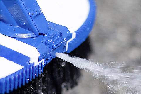 Nahaufnahme eines blauen Hochdruckreinigersprühaufsatzes, der einen starken Wasserstrahl auf eine Oberflächenreinigung richtet.