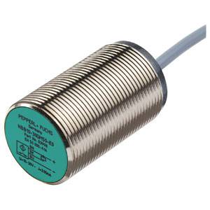 Zylindrischer induktiver Sensor mit Metallgehäuse und grünem Frontaufsatz, angeschlossener Kabelverbindung zur Erkennung von Objekten.
