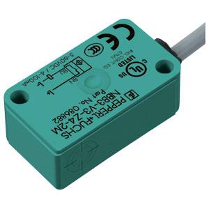 Ein rechteckiger, grüner Näherungssensor mit mehreren Zertifizierungen und technischen Spezifikationen auf der Oberseite. Ein Kabel ist angeschlossen.