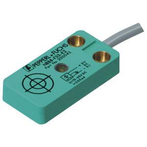 Ein rechteckiger induktiver Sensor von Pepperl+Fuchs mit Kabelanschluss. Der Sensor ist grün mit einer Markierung und Schraublöchern.