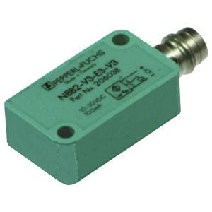 Ein rechteckiger grüner Sensor mit der Aufschrift 'Pepperl+Fuchs' und weiteren technischen Details. Er hat eine kleine Metallverbindung.