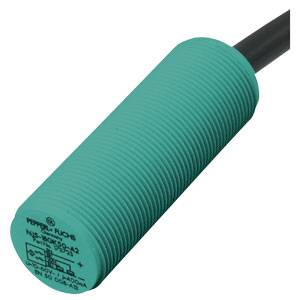 Ein zylindrischer, grüner nähe Sensor mit Kabel. Oben sind Markierungen und technische Informationen aufgedruckt.
