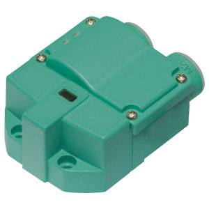 Ein quadratischer, grüner Sensor mit zwei seitlichen Schrauben, möglicherweise ein Näherungssensor, auf weißem Hintergrund.