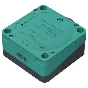 Ein quadratischer, grüner Induktivsensor von Pepperl+Fuchs mit Schraubanschlüssen und technischen Angaben auf der Oberseite.