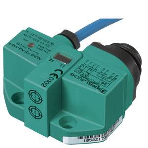 Ein eckiger, grüner Sensor mit CE-Kennzeichnung. Oben befindet sich ein schwarzes Kabel. Verwendet in Automatisierungstechnik.