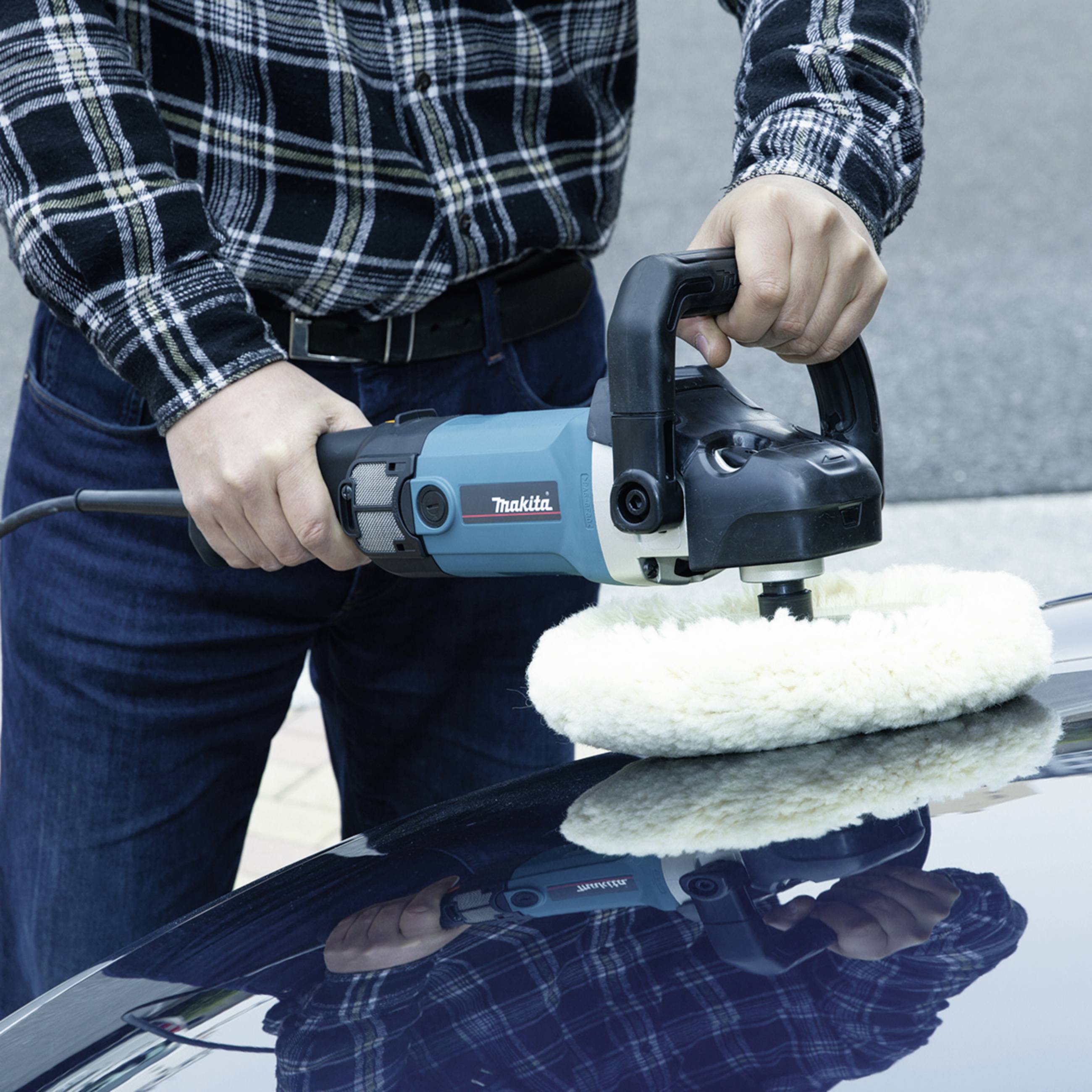 Eine Person poliert mit einer blauen Poliermaschine die Motorhaube eines Autos. Die Poliermaschine hat einen weißen Aufsatz.
