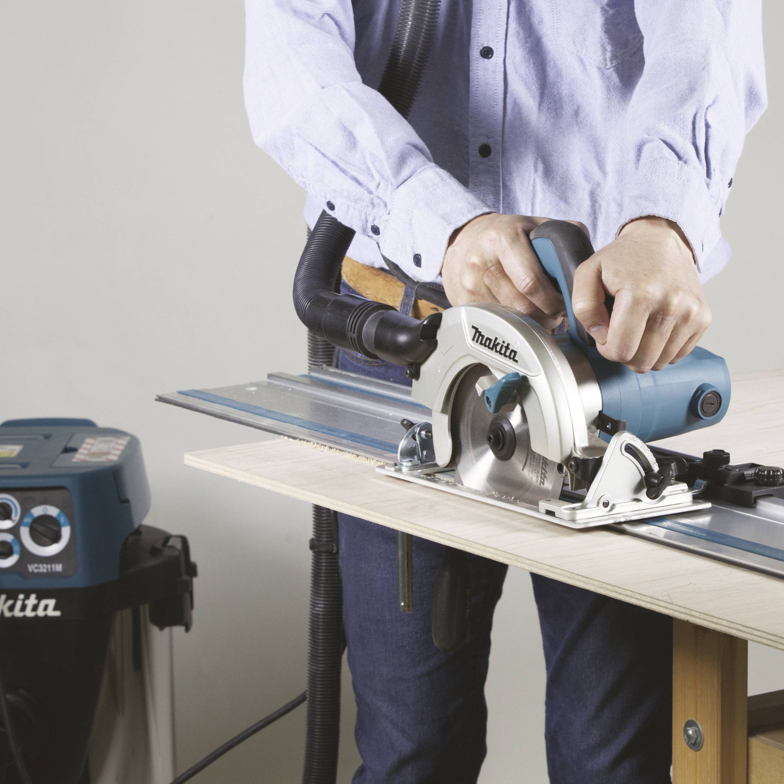 Eine Person verwendet eine Handkreissäge, um ein Brett zu schneiden. Das Werkzeug ist von der Marke Makita und zeigt präzise Arbeit.
