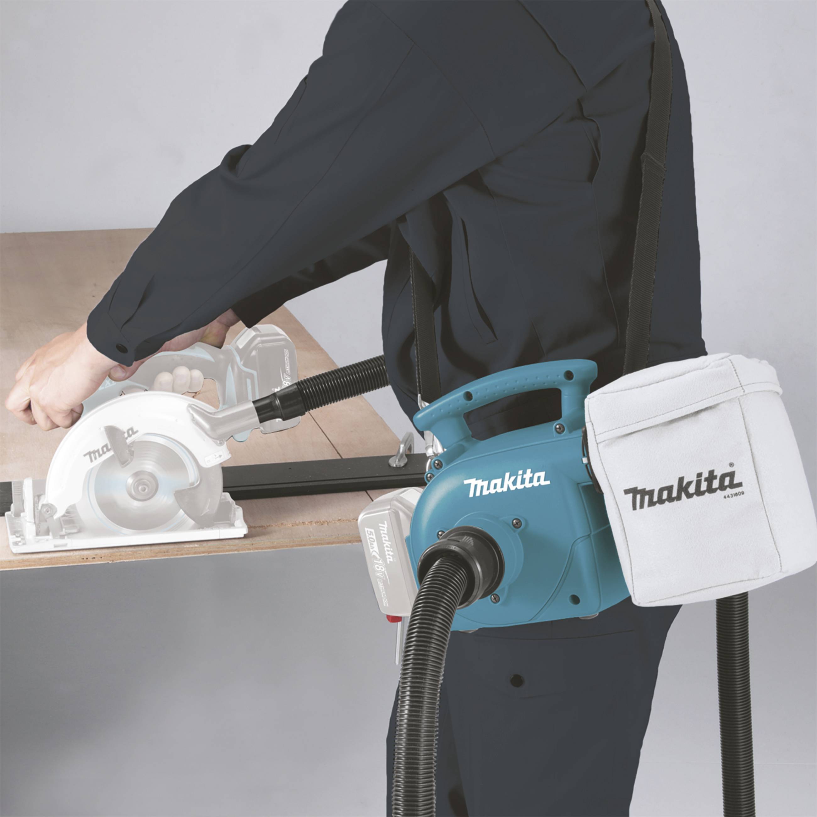 Eine Person sägt mit einer elektrischen Handkreissäge von Makita Holz. Staub wird in einem angeschlossenen Beutel gesammelt.