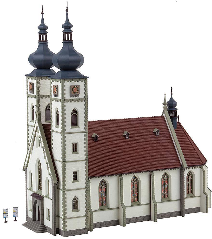 Eine Kirche mit roten Ziegeldächern und zwei hohen Türmen mit Zwiebeldächern. Die Fassade ist weiß mit dekorativen Elementen.