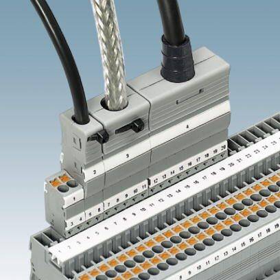 Ein grauer elektrischer Anschlussblock mit nummerierten Terminalklemmen und zwei angeschlossenen Kabeln vor blauem Hintergrund.