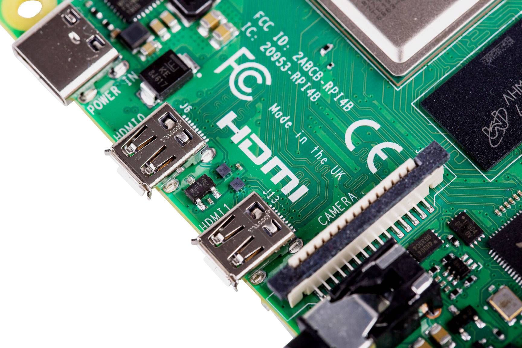 Nahaufnahme einer grünen Leiterplatte eines Einplatinencomputers mit HDMI- und USB-Anschlüssen, zahlreichen elektronischen Komponenten und einem Kameraanschluss.