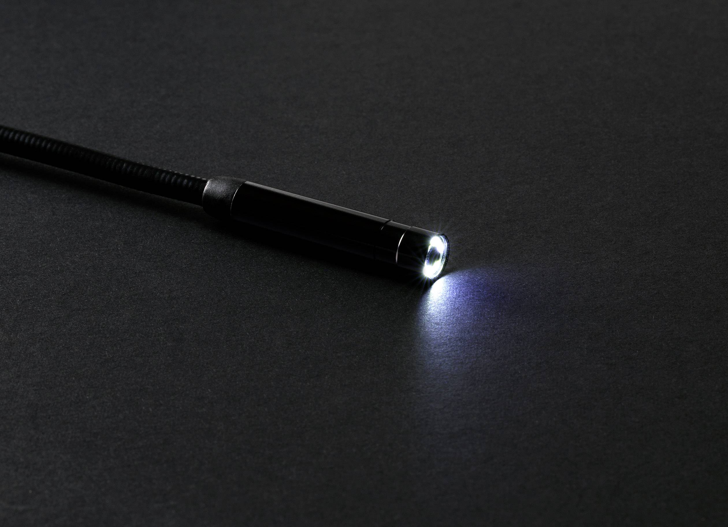 Kleine Taschenlampe leuchtet auf dunklem, neutralem Hintergrund.