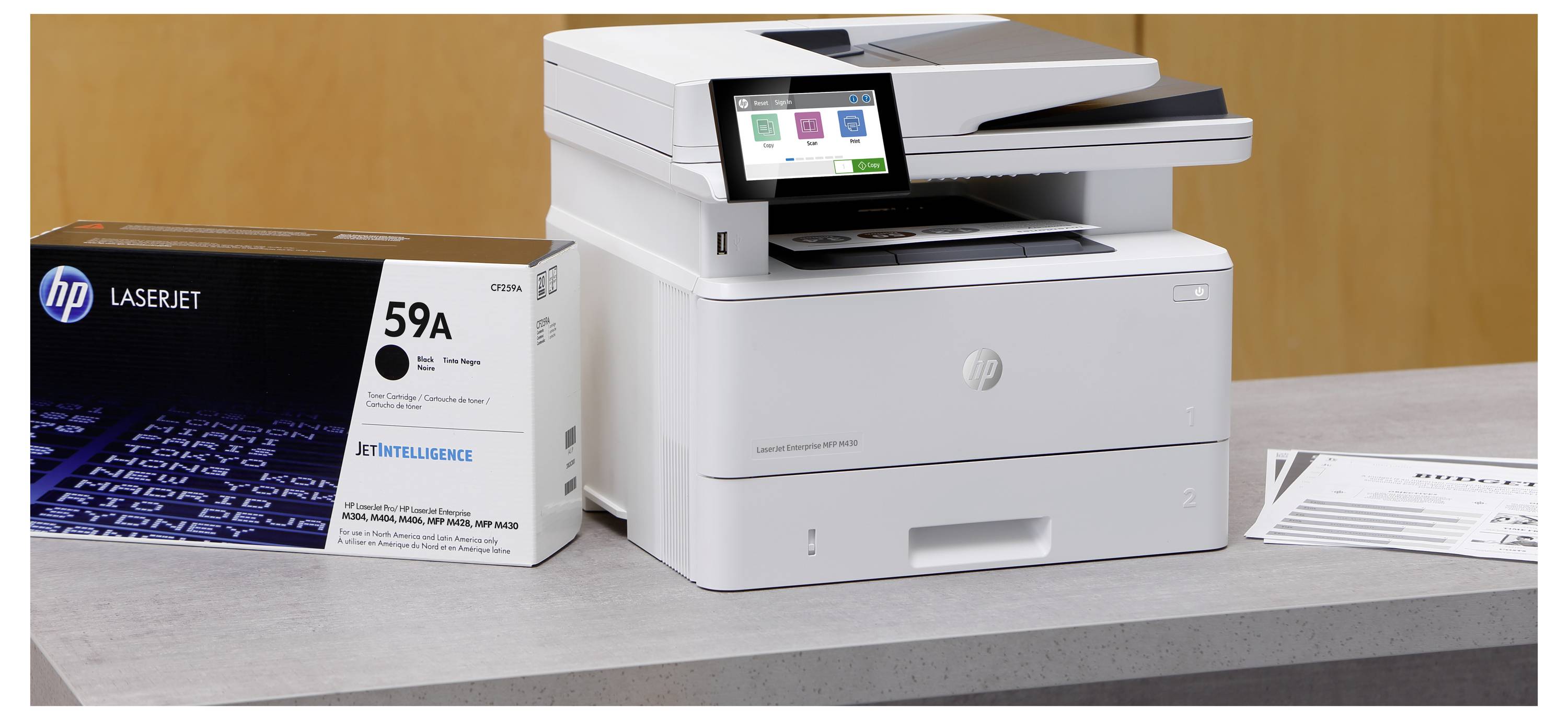 HP LaserJet Drucker auf einem Schreibtisch neben einer „59A" Tonerkartusche und einem bedruckten Blatt, das Bürodruckausrüstung zeigt.