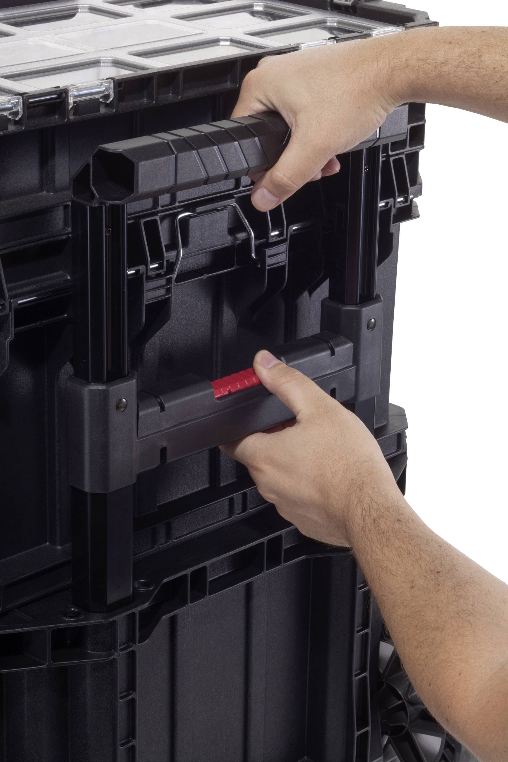 Hände greifen den Griff eines gestapelten, schwarzen Aufbewahrungsbehälters mit verriegelbarem System.